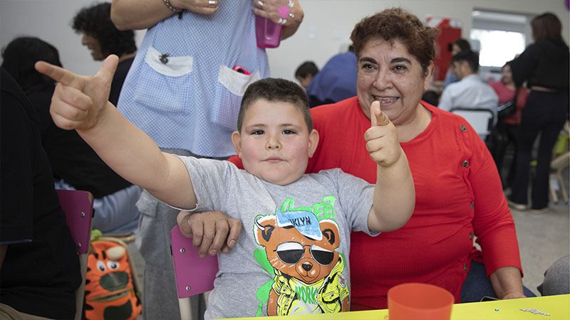 Una madre y su hijo están sentados en una mesa durante la jornada del Día Nacional del Derecho a la identidad.