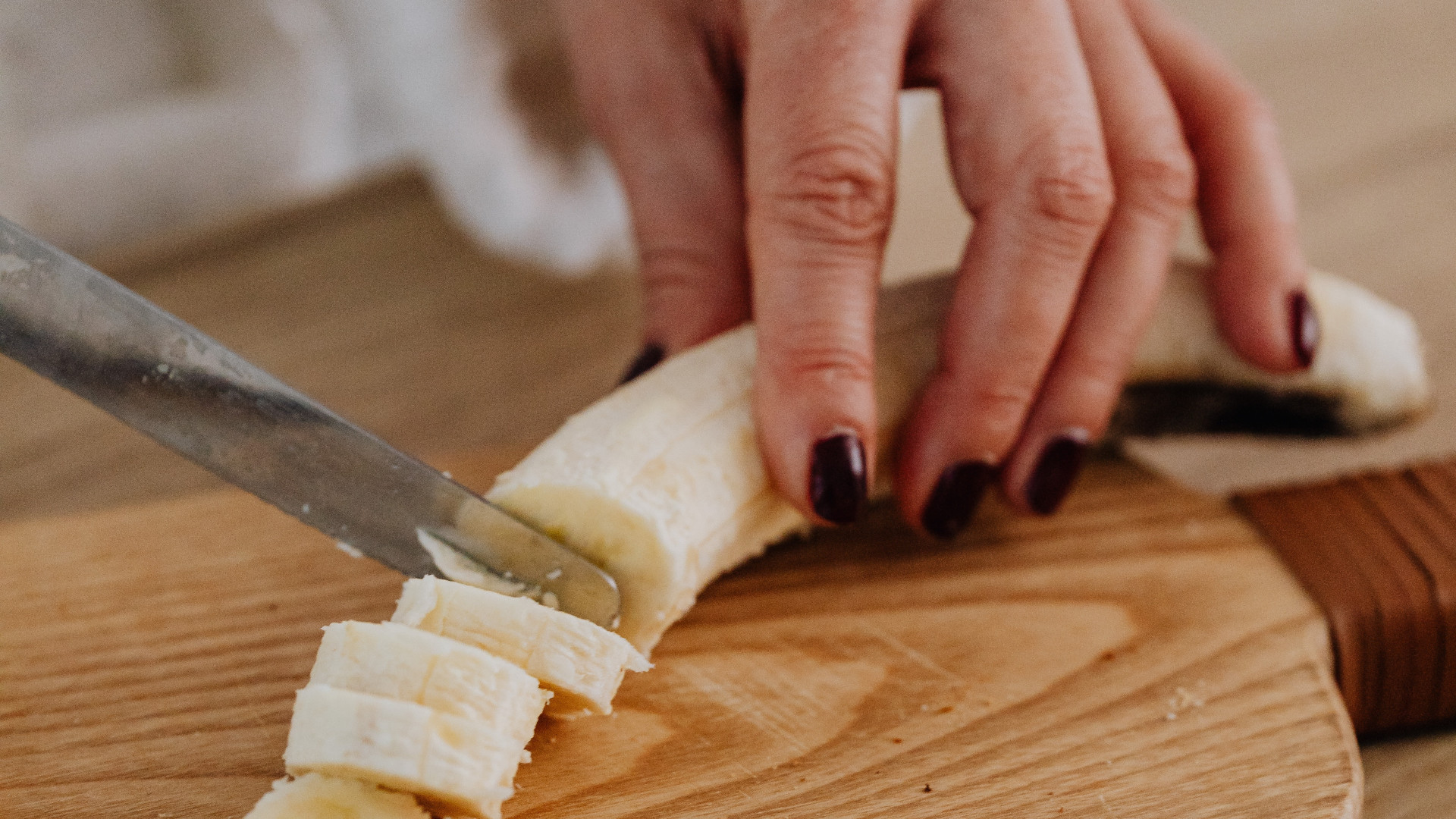 Plano detalle de una mano femenina cortando una banana en rodajas