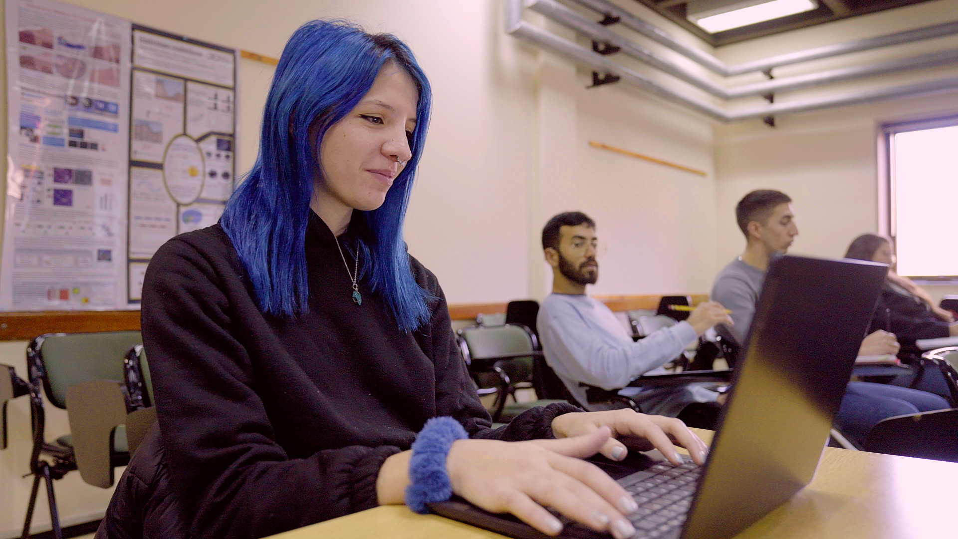 Estudiante mujer del Instituto Sabato anota en  su computadora