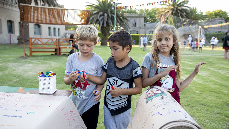 Tres niños se encuentran coloreando en una de las actividades dentro del predio del Espacio Unzué.