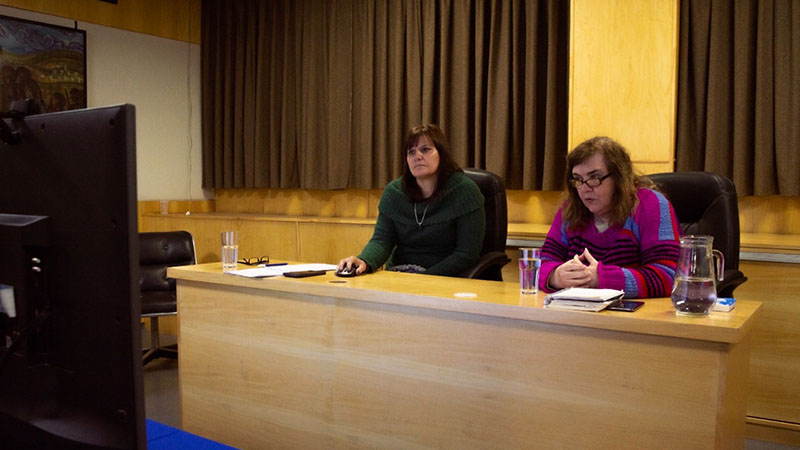 Las capacitadoras se encuentras sentadas en el escritorio durante el encuentro mientras se transmitía virtualmente la jornada.