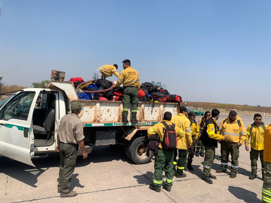 Brigadistas y bomberos descargando bolsos antes de ser embarcados en la aeronave de la Fuerza Aérea Argentina