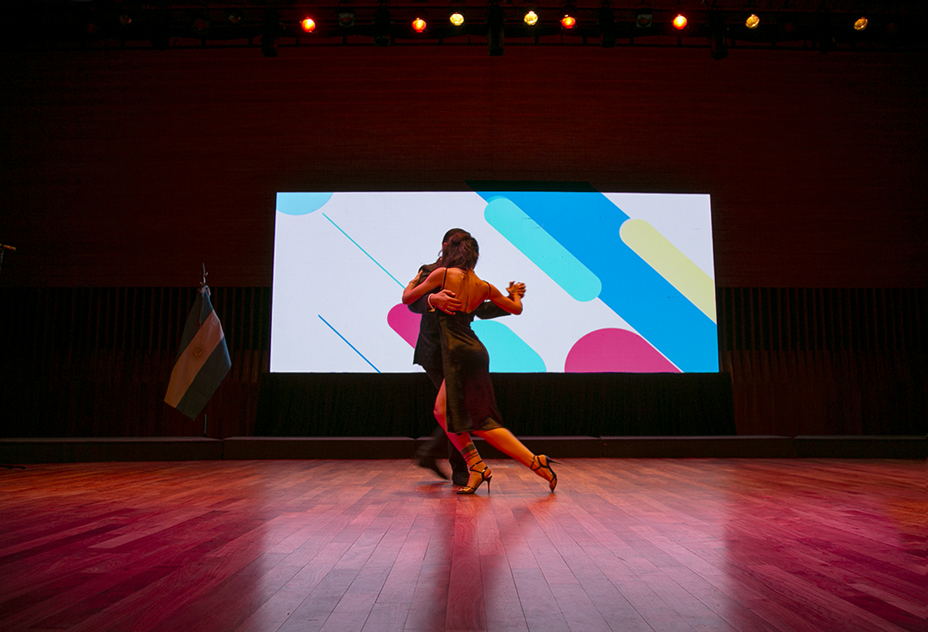 Una pareja baila tango en el escenario del acto