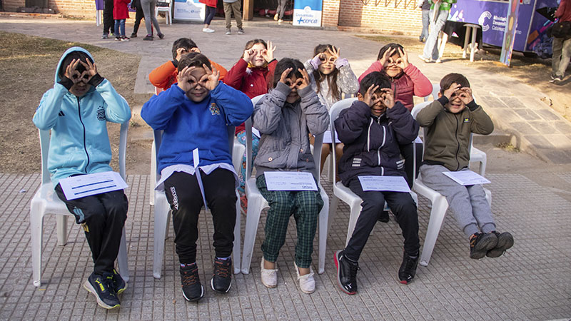 Chicos sentados en sillas esperando a que sean atendidos para su examen de agudeza visual.