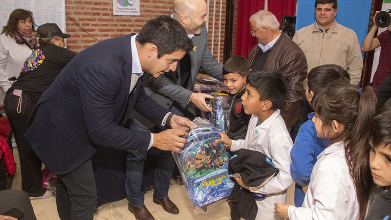 Un funcionario le está entregando a los alumnos útiles escolares.