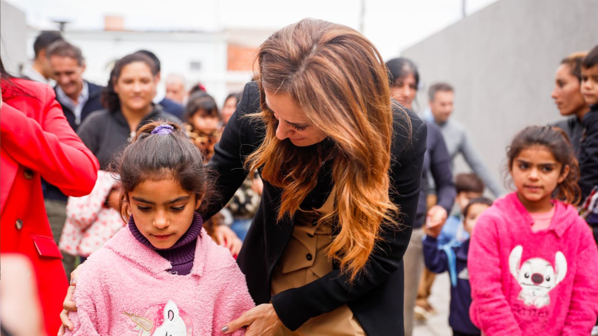 La ministra agachada tomando a una niña de la mano en la inauguración del CDI en Malvinas Argentinas.