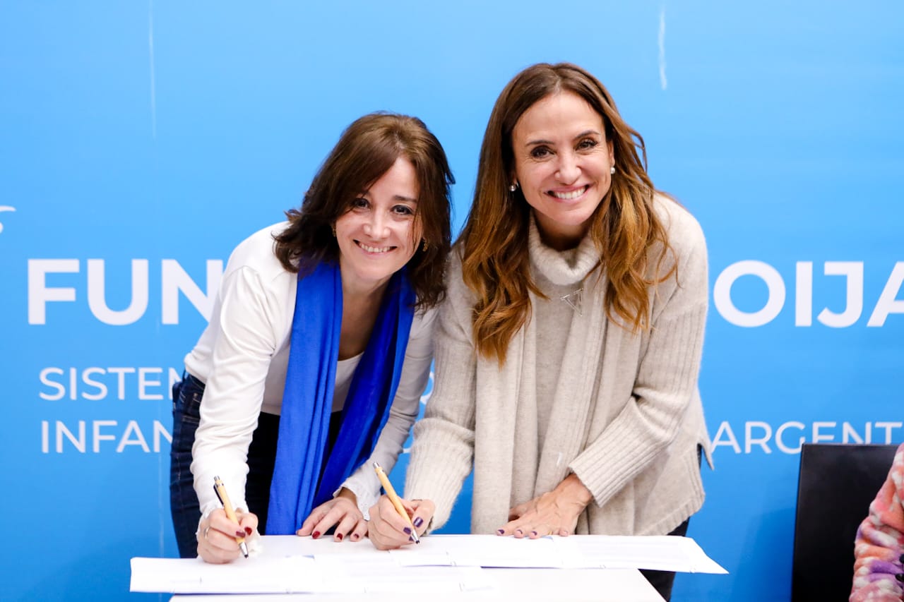 La ministra de Desarrollo Social de la Nación, Victoria Tolosa Paz junto a una mujer titular de la Fundación Sistema de Orquestas Infantiles, firmando un acuerdo.