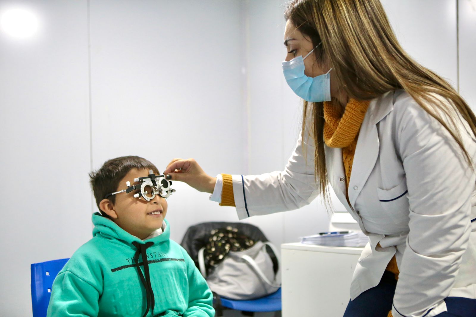 Un niño se esta realizando un examen de agudeza visual con una oftalmóloga para luego entregarle un par de anteojos.