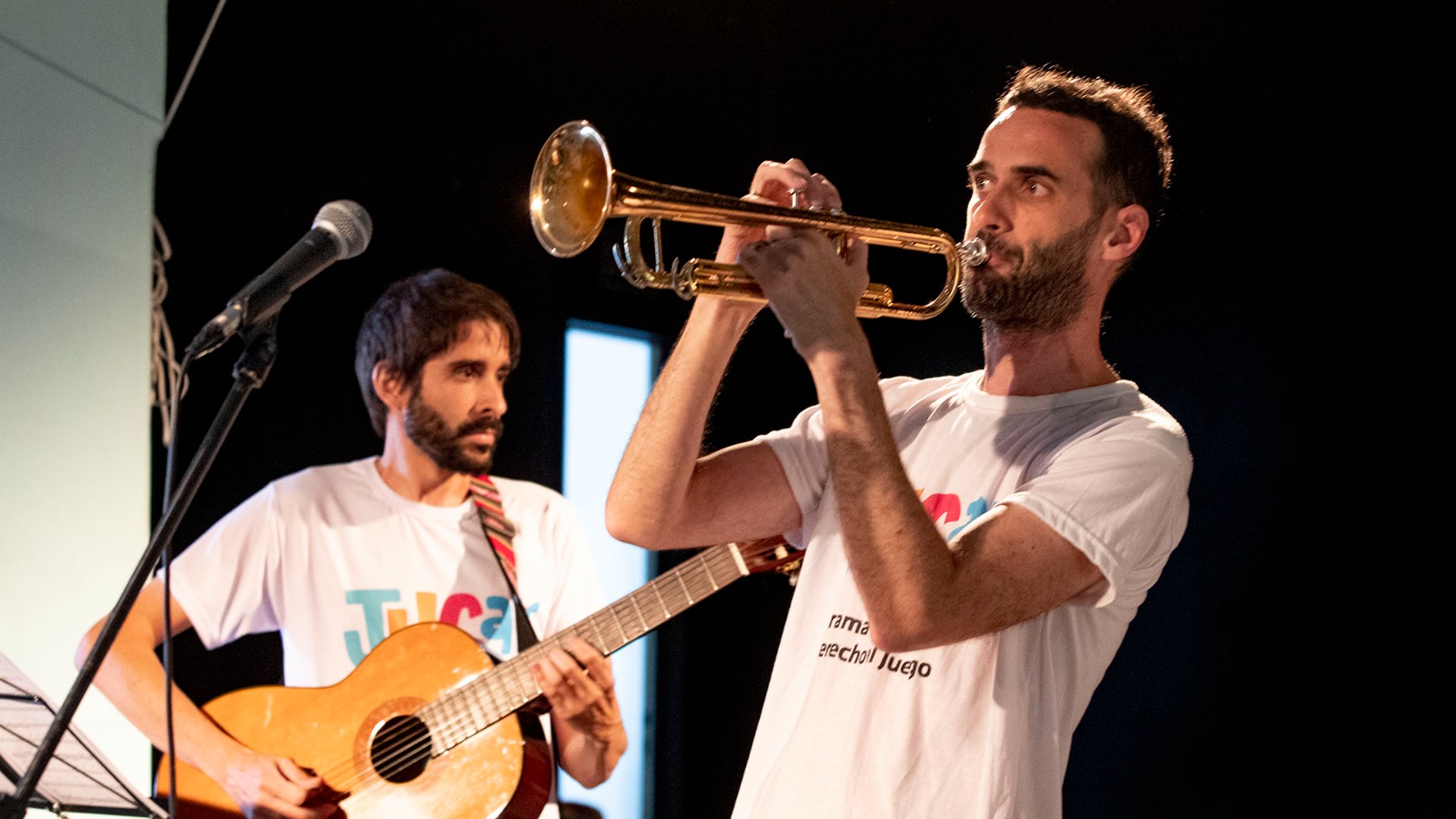 Músicos tocando la trompeta y la guitarra arriba de un escenario.